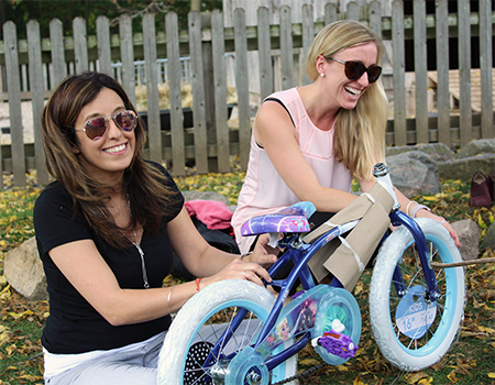 Two smiling women assembling a bicyle