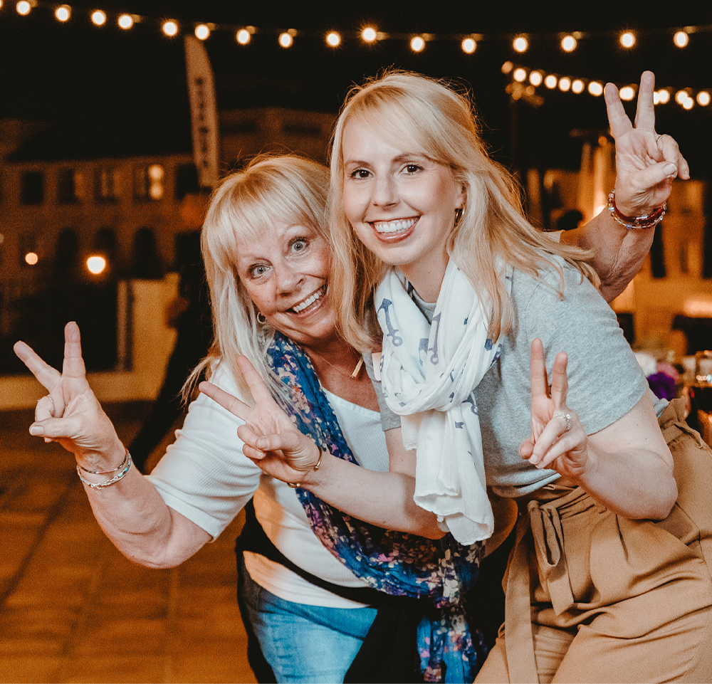 Two women givig the peace sign with their fingers